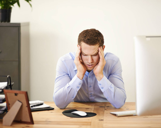 Si seulement le stress brûlait les calories. Un homme d'affaires accablé assis à son bureau, la tête dans les mains. - Photo, image
