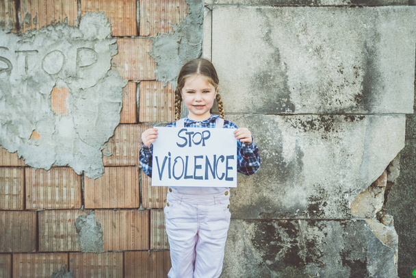 Kind meisje met een poster met geschreven STOP VIOLENCE ter ondersteuning van de vrede. Concept "geen oorlog" in Oekraïne en in de wereld. - Foto, afbeelding