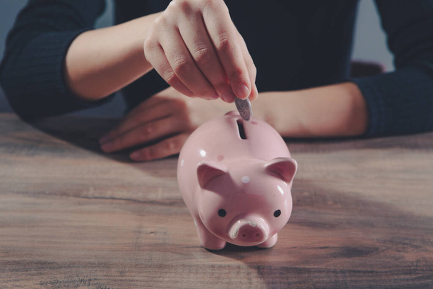 Young woman  putting a coin inside piggy bank as savings for investment - Foto, Imagem