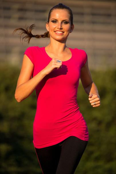 Preety young woman running on a track - Photo, Image
