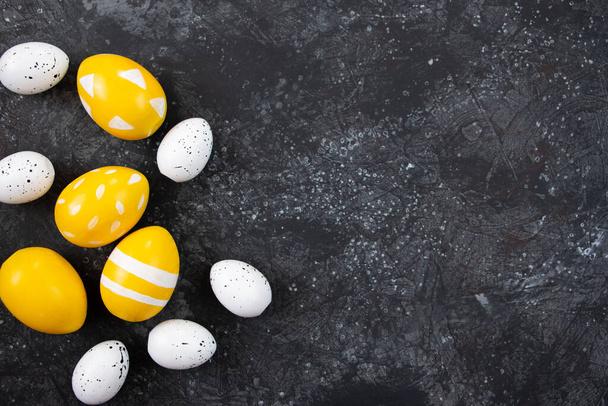 Huevos amarillos de Pascua sobre fondo negro, feliz concepto de Pascua. Fondo festivo, plano laico. - Foto, Imagen