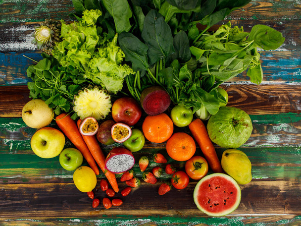 Top view close up shot of various kinds of healthy tasty nutritious fresh natural organic agriculture vegan vegetables and fruits ingredient diet placed on old colorful wooden table background. - Фото, изображение