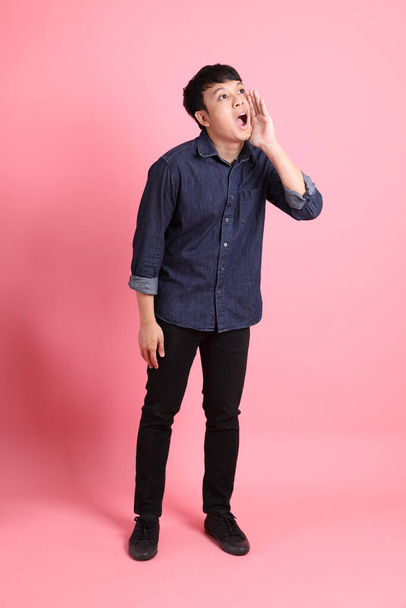 The young adult Asian man standing on the pink background. - Fotó, kép
