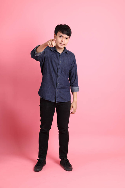 The young adult Asian man standing on the pink background. - Photo, image