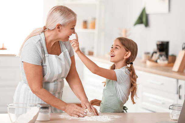 Felnőtt nő a kis unokájával, aki tésztát keres a konyhában. - Fotó, kép