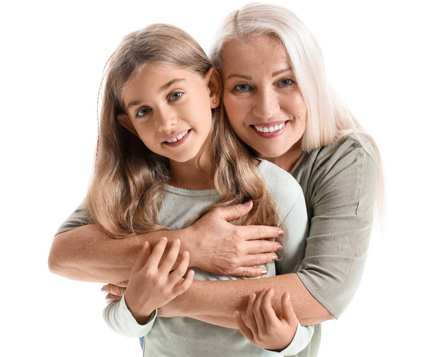Reife Frau umarmt ihre kleine Enkelin auf weißem Hintergrund - Foto, Bild