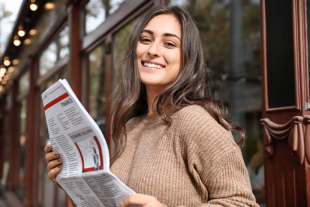 Beautiful young woman with newspaper on city street - Φωτογραφία, εικόνα