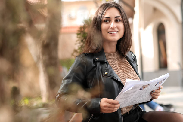 Stílusos fiatal nő olvas újságot padon szabadban - Fotó, kép
