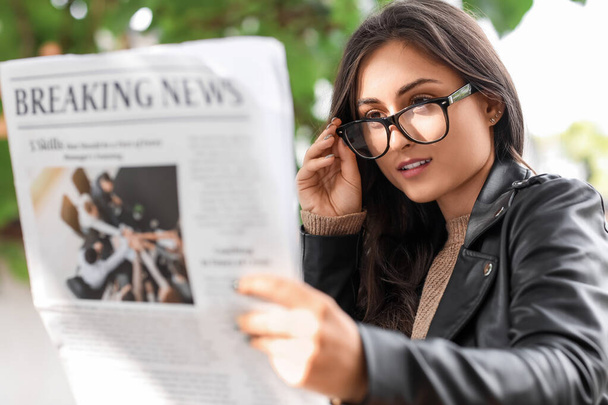 Young woman in eyeglasses reading newspaper outdoors - Zdjęcie, obraz