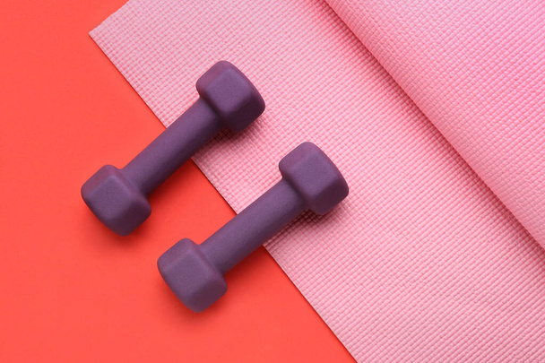 Stylish dumbbells and fitness mat on red background - Fotografie, Obrázek