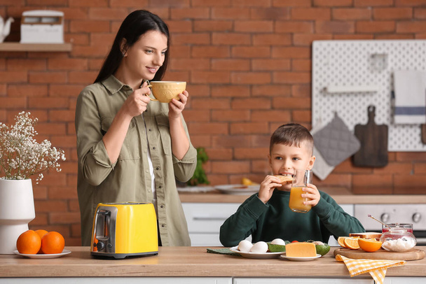 Kleiner Junge mit seiner Mutter isst Toastbrot in der Küche - Foto, Bild