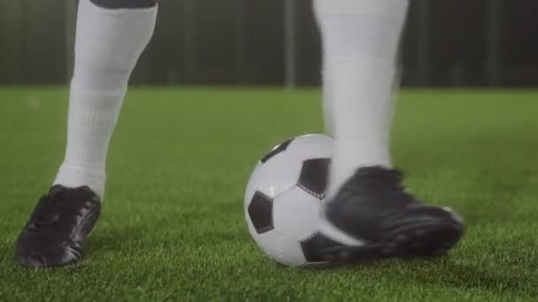 Çerçevede bacakları olan düşük açılı bir sporcu sadece yeşil çimlerin üzerinde futbol topu etrafında numaralar yapıyor. - Video, Çekim