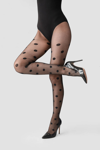 Beautiful young woman in black tights on light background - Foto, afbeelding