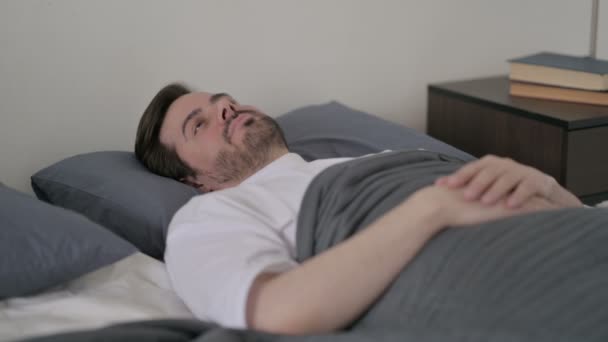 Jeune homme se réveille au lit en pensant - Séquence, vidéo