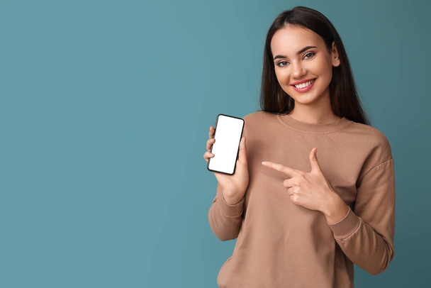 Beautiful young woman with mobile phone on blue background - Φωτογραφία, εικόνα