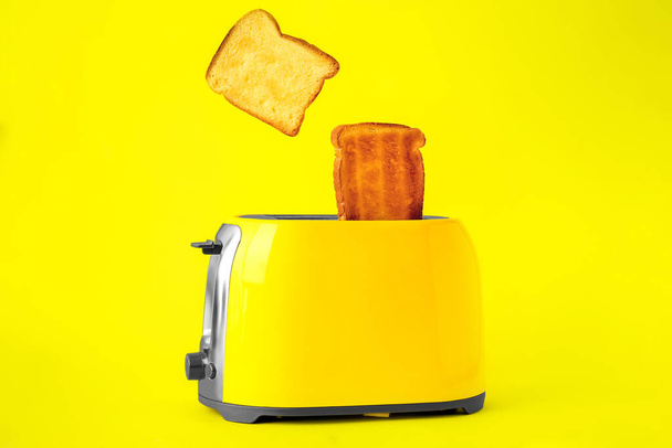 Tostadora moderna con rebanadas de pan sobre fondo amarillo - Foto, Imagen