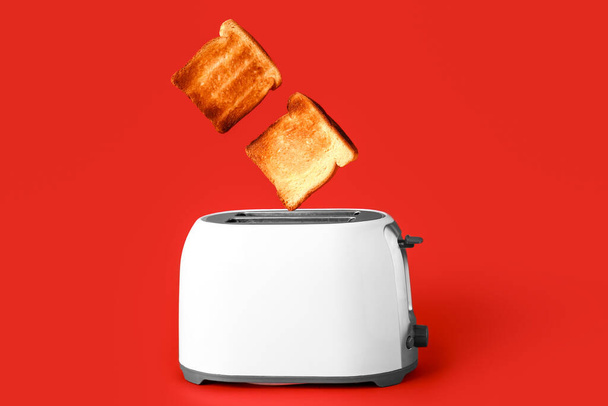Modern toaster with bread slices on red background - Photo, Image