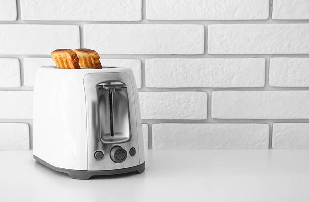 Moderner Toaster mit Brotscheiben auf hellem Tisch - Foto, Bild
