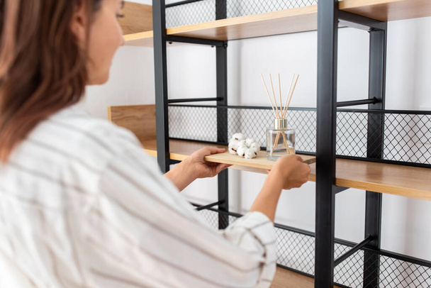 woman placing aroma reed diffuser to shelf home - Фото, зображення