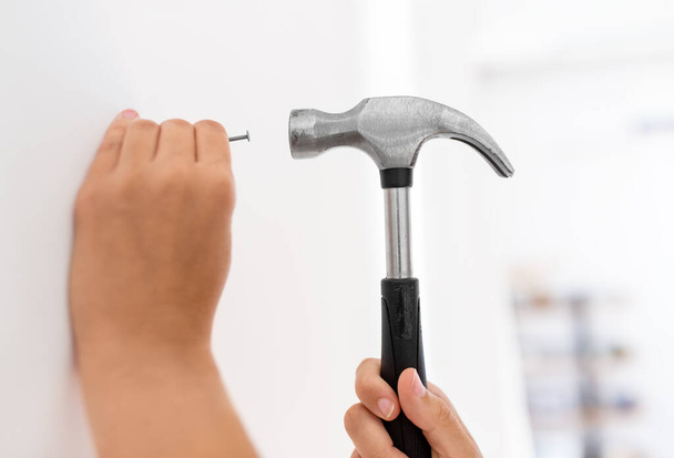 close up of hands hammering nail to wall at home - Foto, imagen