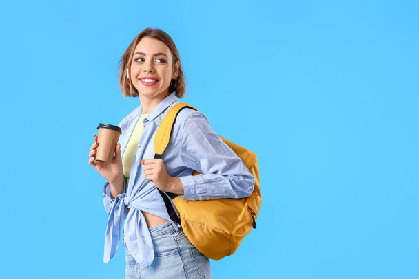 Vrouwelijke student met koffie op blauwe achtergrond - Foto, afbeelding