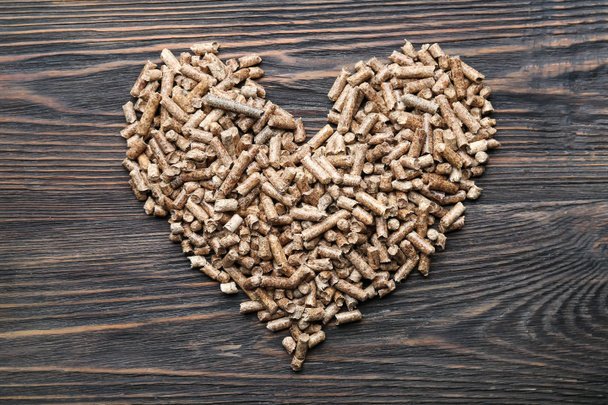 Heart made of wood pellets on wooden background - 写真・画像