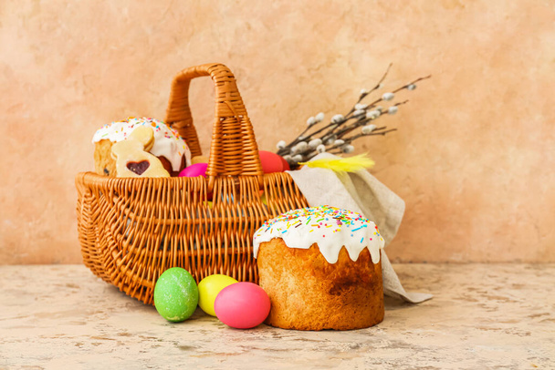 Gift basket with painted Easter eggs and cakes on beige background - Valokuva, kuva