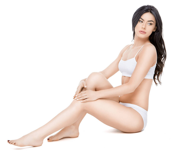 Fitness young woman with a beautiful body sitting on white background - Fotó, kép
