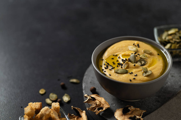 вегетарианский суп с шампиньонами на темном фоне с семенами и гренками, место для текста - Фото, изображение
