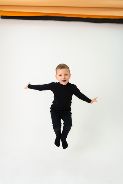 A little boy jumping with outstretched arms on a white background - Photo, Image
