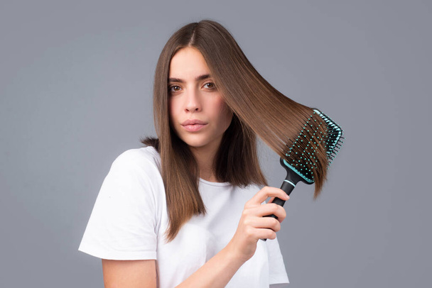 Woman brushing hair with comb. Beautiful girl combing long hair with hairbrush. - Fotó, kép