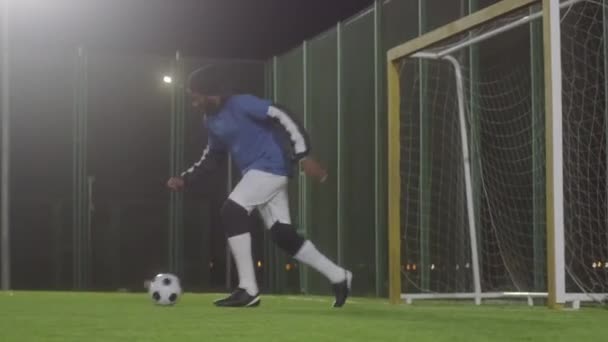 Szerokie śledzenie dopasowany młody czarny mężczyzna sportowiec robi sztuczki z piłką nożną, biegnie w tę i z powrotem na zielonej trawie na boisku do piłki nożnej - Materiał filmowy, wideo