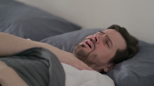 Молодой человек кашляет, когда спит в постели - Кадры, видео