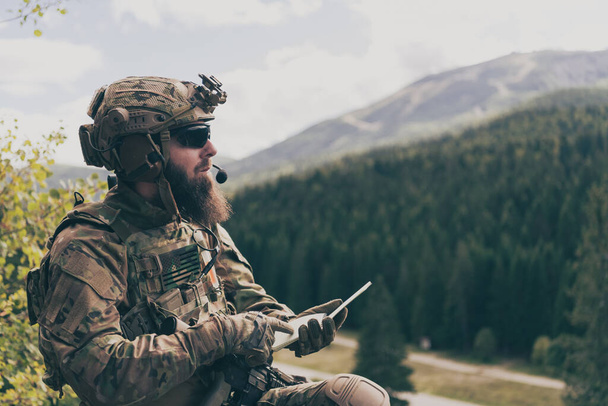 War concept. Bearded soldier in uniform of special forces in dangerous military action in dangerous enemy area studies attack tactics. Selective focus. High-quality photo - Фото, изображение
