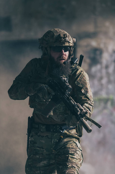 A bearded soldier in the uniform of special forces in dangerous military action in a dangerous enemy area. Selective focus. High-quality photo - Фото, зображення