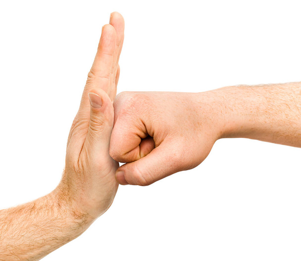 una mano apretada en un puño golpea la mano mostrando una señal de stop, sobre un fondo blanco aislado - Foto, Imagen