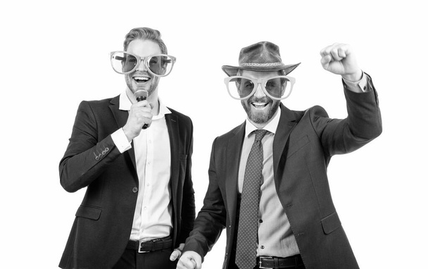 Funcionários felizes se divertem cantando karaoke em óculos engraçados e roupas formais, festa corporativa - Foto, Imagem