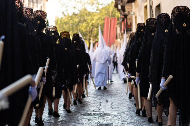 Rear view of religious women dressed in black mantillas in a Catholic procession during Holy Week in Granada, Spain.  - Photo, Image