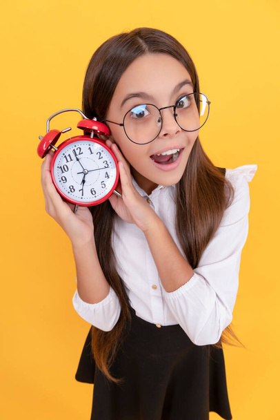 amazed child in school uniform and glasses listen alarm clock ringing showing time, amazement - Foto, Imagen