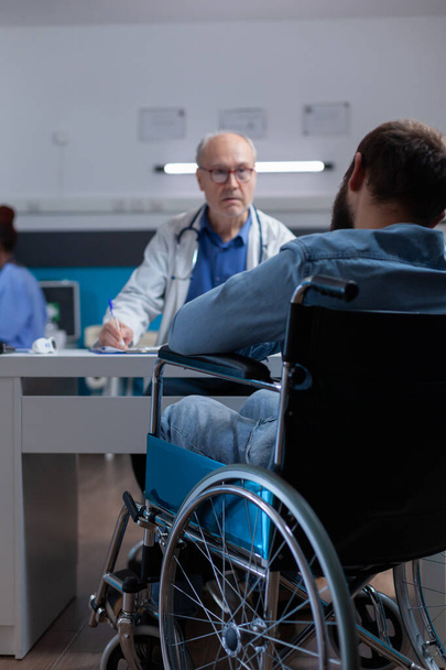 Pacient sedí na invalidním vozíku setkání s odborníkem na prohlídku léčit nemoci - Fotografie, Obrázek