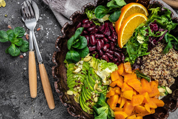 Quinoa saláta tálban avokádóval, édesburgonya, bab szürke háttérrel. szuperkaja koncepció. Egészséges, tiszta étkezési koncepció. Vegán vagy gluténmentes diéta. felülnézet. - Fotó, kép