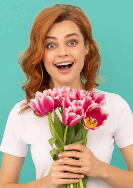 surprised girl with tulip flower bouquet on blue background - Фото, изображение