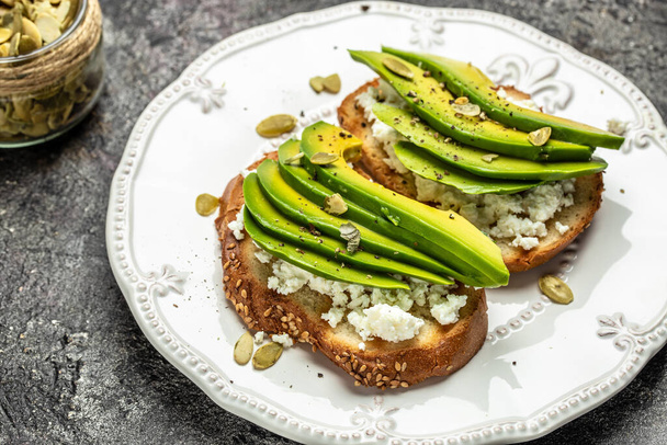 Avokado çavdar ekmeği, dilimlenmiş avokado, kahvaltıda ya da öğle yemeğinde kabak çekirdeği. Vejetaryen sandviçler. Sağlıklı, temiz yeme konsepti. Vejetaryen ya da glütensiz diyet. en üstteki görünüm. - Fotoğraf, Görsel