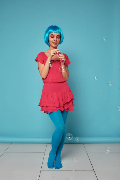 Красива молода жінка з блакитною перукою і яскравим макіяжем в мильних бульбашках. Модна модель дівчини з креативним кольоровим макіяжем. Жіноча концепція ляльок
. - Фото, зображення