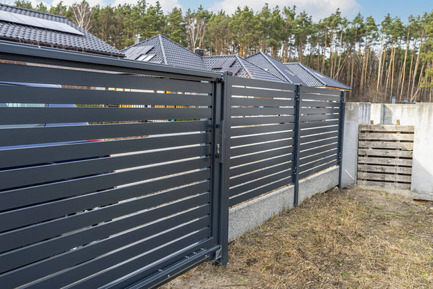 Moderner anthrazitfarbener Zaun, sichtbares Schiebetor zur Garage, Blick vom Garten. - Foto, Bild