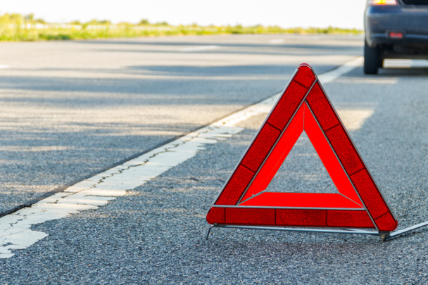Červená značka nouzového zastavení (červená trojúhelníková výstražná značka) a rozbité auto na silnici - Fotografie, Obrázek