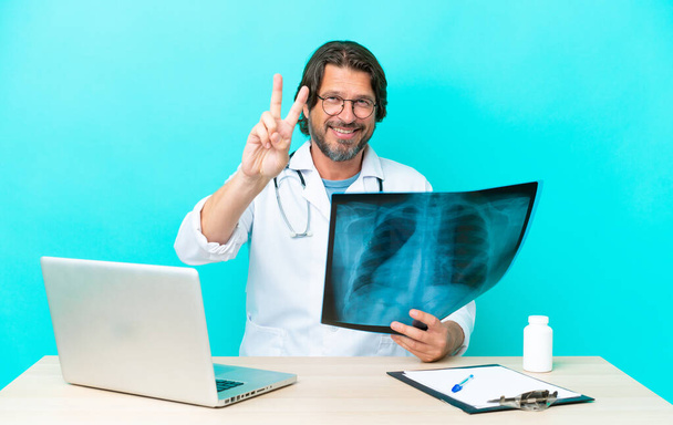 Професійний лікар-травматолог в офісі посміхається і показує знак перемоги
 - Фото, зображення