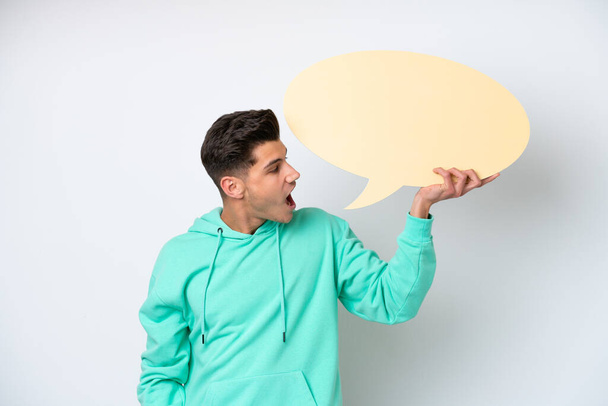 Young handsome caucasian man isolated on white bakcground holding an empty speech bubble - Фото, зображення