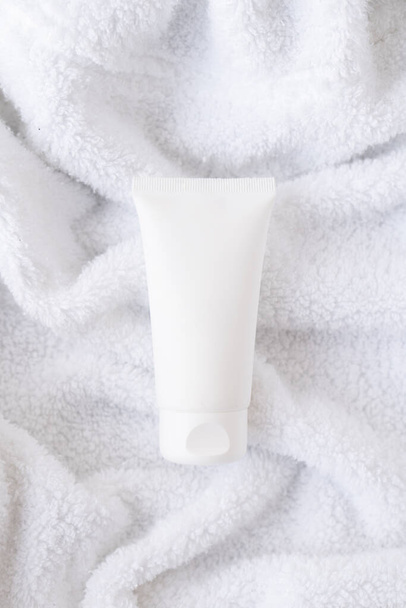 Čisté bílé kosmetické krém trubice na nadýchané bílé bavlněné ručník pozadí, maketa-up a design připraven - Fotografie, Obrázek