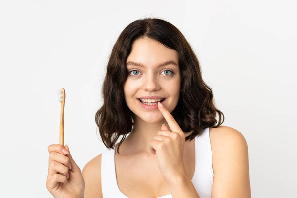 Teenager Ukrainian girl isolated on white background with a toothbrush and happy expression - Valokuva, kuva